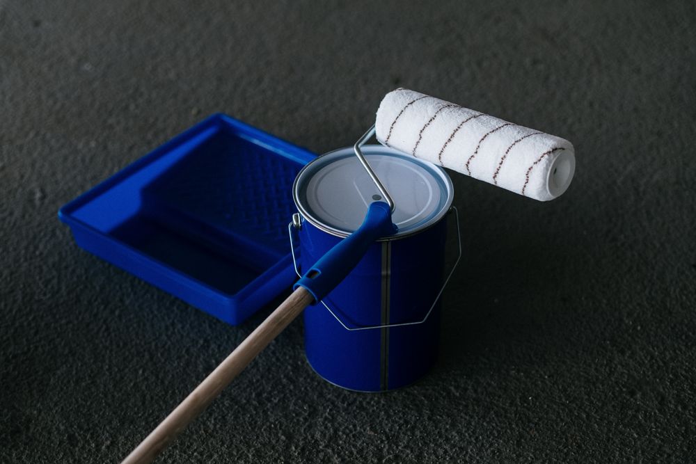 A closed paint can with a roller and tray beside it