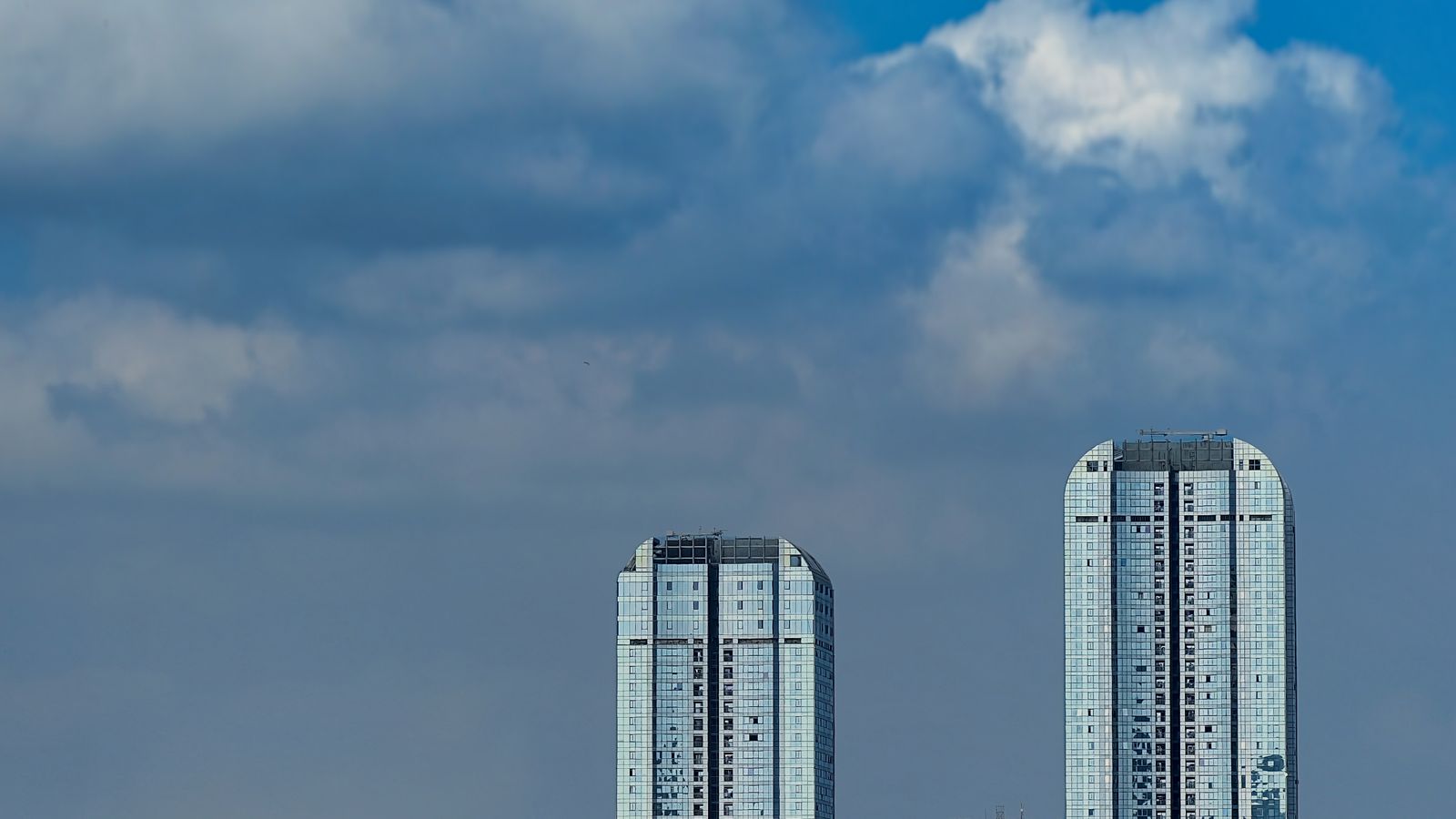 Two glass-fronted office towers rising into a cloudy sky