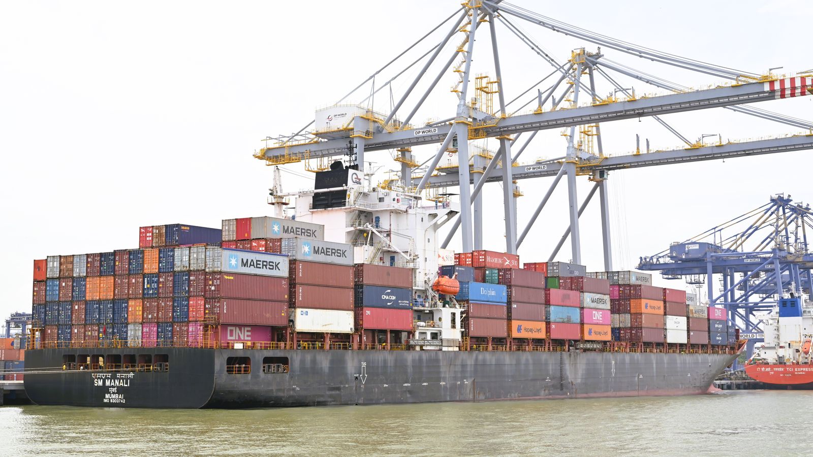 Container ship docked beside tall port cranes with stacked containers