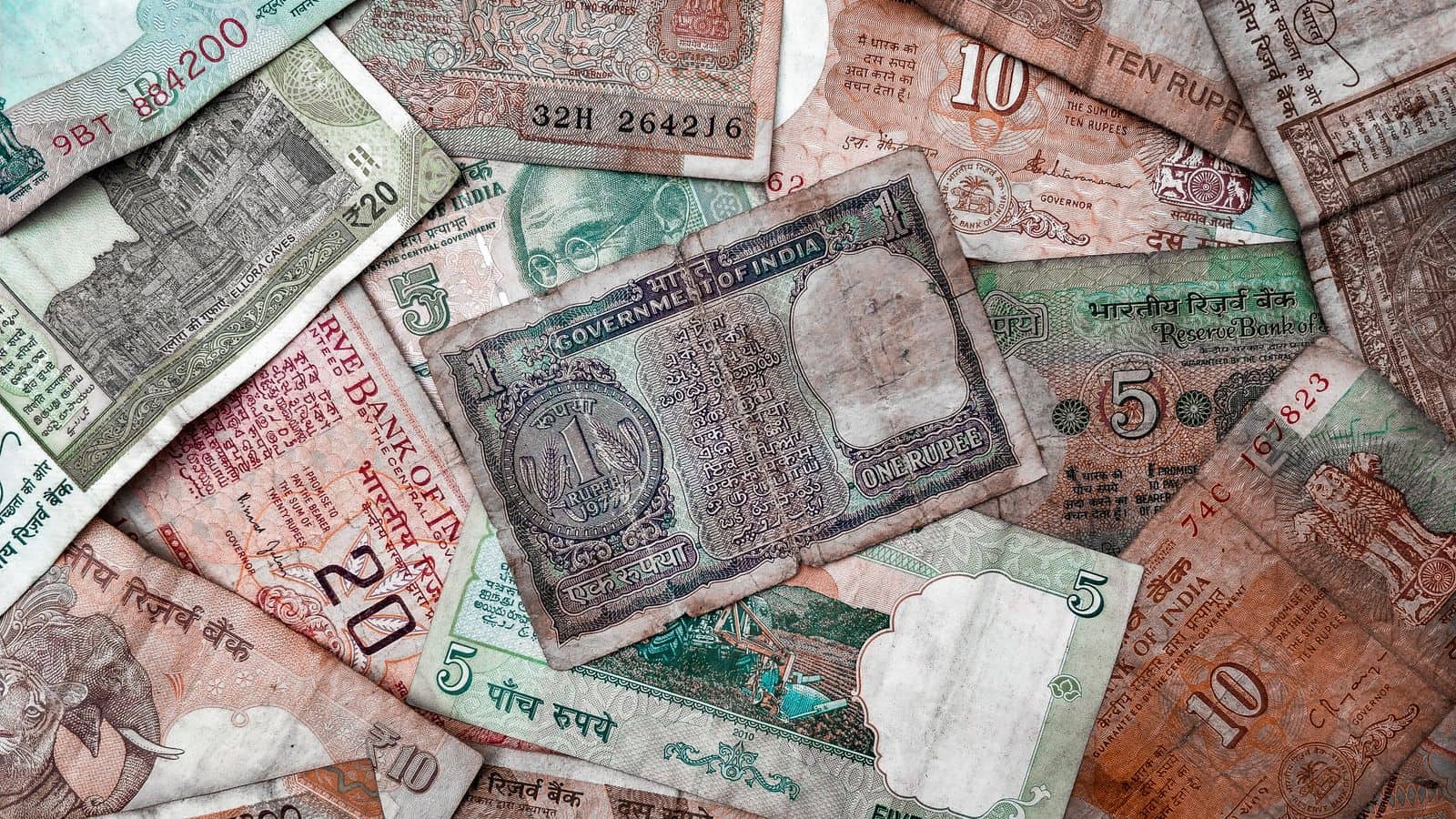Old Indian rupee banknotes of several denominations spread out together