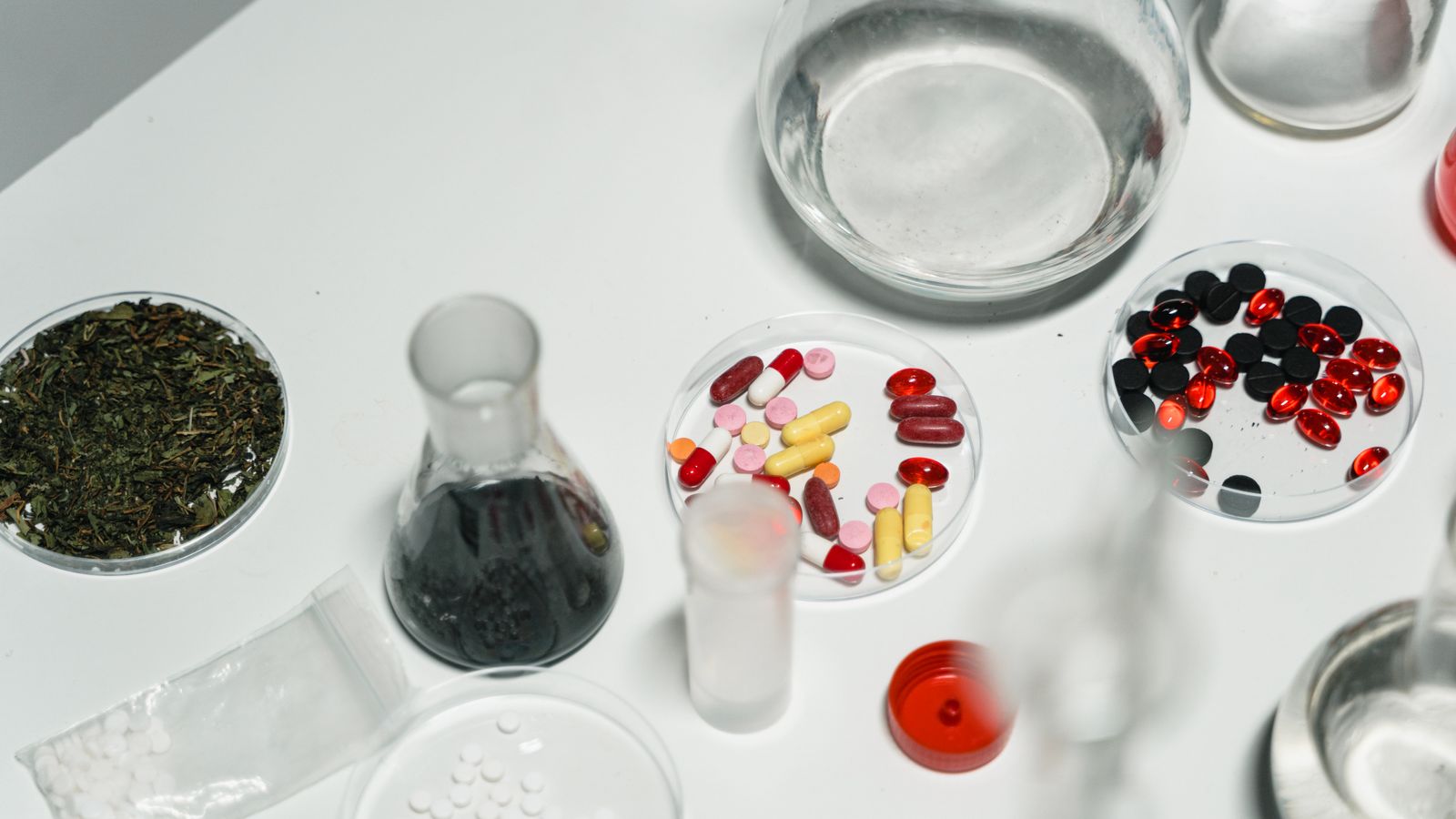Pills, capsules and glass dishes on a white laboratory surface